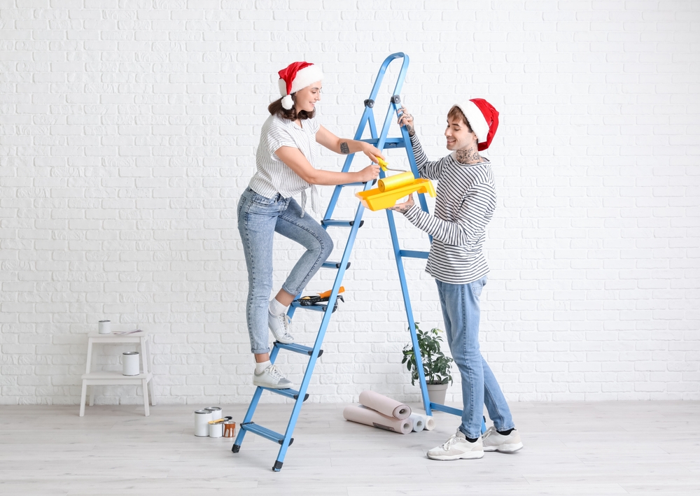 Young,Couple,With,Santa,Hats,And,Paint,Roller,During,Repair